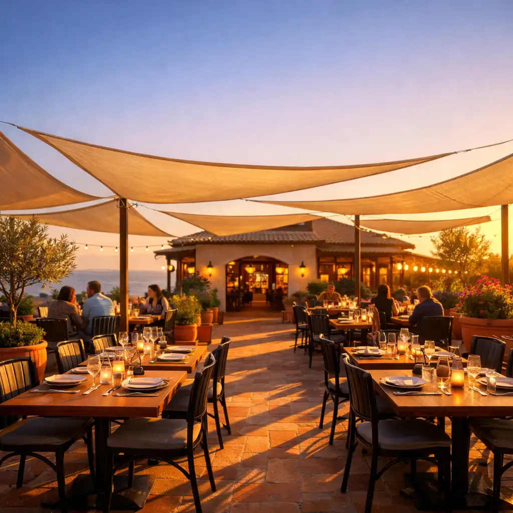 Terrasse élégante au coucher du soleil avec tables dressées, voiles d'ombrage et plantes méditerranéennes